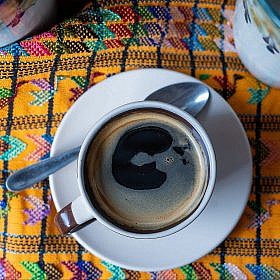 Photo of coffee in cup on brocaded tablecloth taken in Guatamala