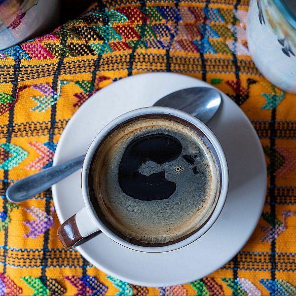 Photo of coffee in cup on brocaded tablecloth taken in Guatamala